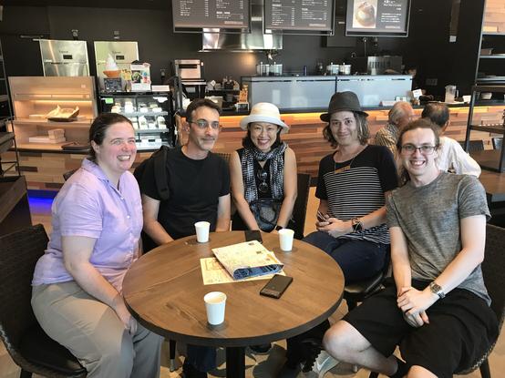 Five smiling people at a cafe table