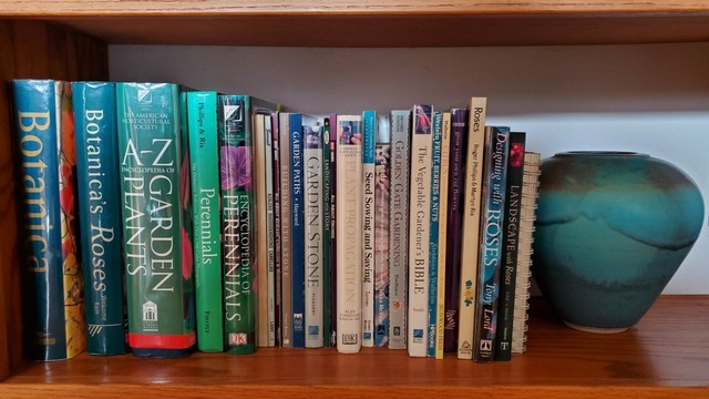 Shelf of gardening books and a large ceramic turquoise vase.