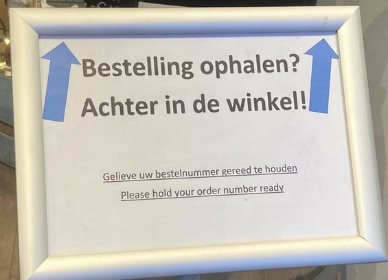 Foto van een bordje uit een winkel met de tekst “gelieve uw bestelnummer gereed te houden” met een slechte Engelse vertaling