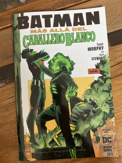 Portada del número 7 de Batman: Más allá del Caballero Blanco. Sobre un fondo blanco se ve en el centro a un personaje que es un esqueleto rodeado de un halo verde como radioactivo. Está sujetando del cuello y levantando del suelo a un personaje que lleva un traje futurista de Batman casi totalmente negro con detalles rojos. Con la otra mano sujeta de la chaqueta a otro personaje que lleva un traje de Batman más clásico. Como no lleva capucha se intuyen pelo y barba blancas. La escena sucede en una azotea.