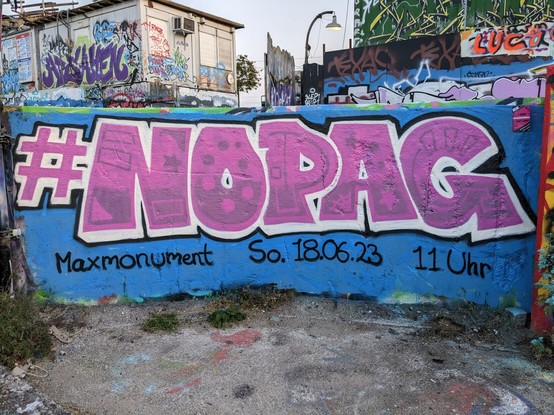 #NOPAG painted on a blue wall with pink spray paint