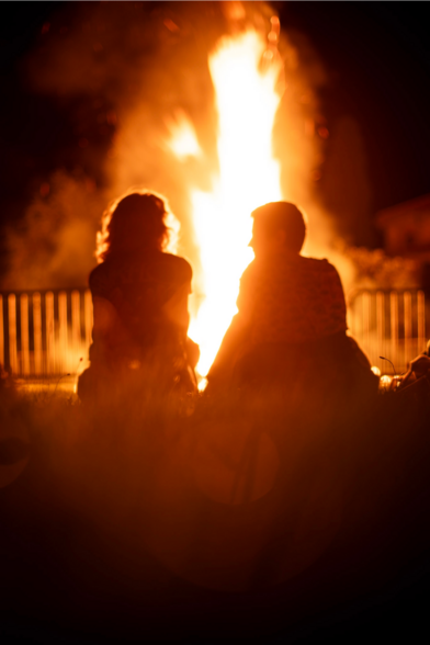 deux personnes en contrejour devant un feu