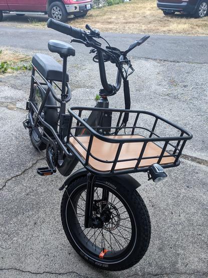 a gray bike with a big front basket, headlight, and long padded seat above the rear wheel