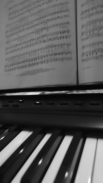 Black and white photo of a digital piano and sheet music.