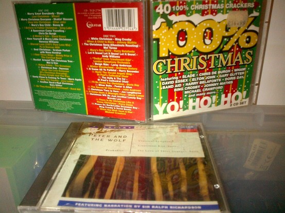 An open jewel case for a "100% Christmas Crackers" CD with red and green themed graphics, next to a closed (and slightly dirty) CD case of recordings of several Prokofiev works, one narrated.