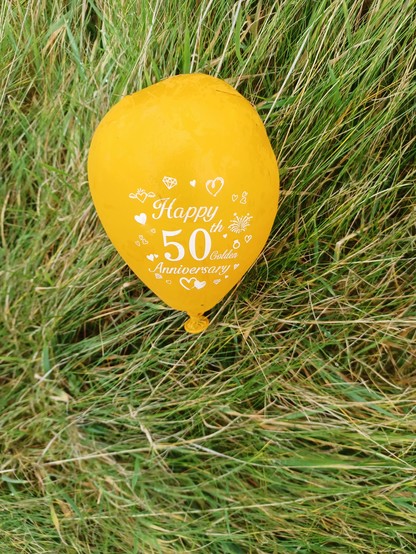 A bright yellow balloon written with the words "Happy 50th Golden Anniversary"