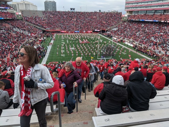 Fans filing in to a a football stadium dressed in red, the home teams colors.