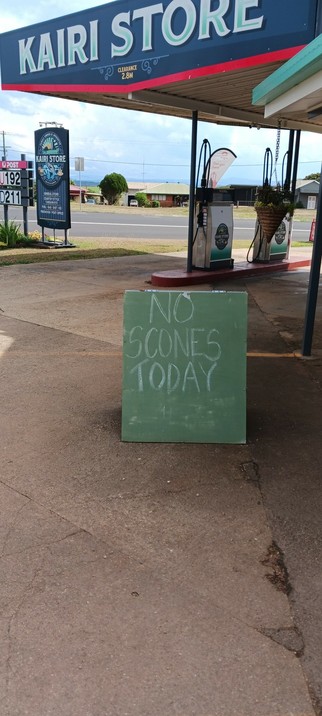 A corner store in a small country town. A chalkboard stands near the entrance, declaring "NO SCONES TODAY"