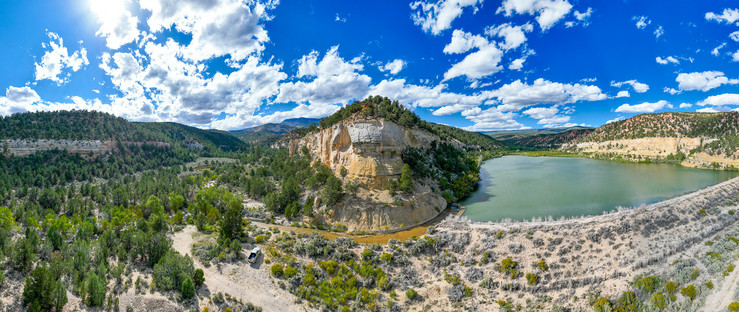 A mountain between a valley of trees and a freshwater lake.