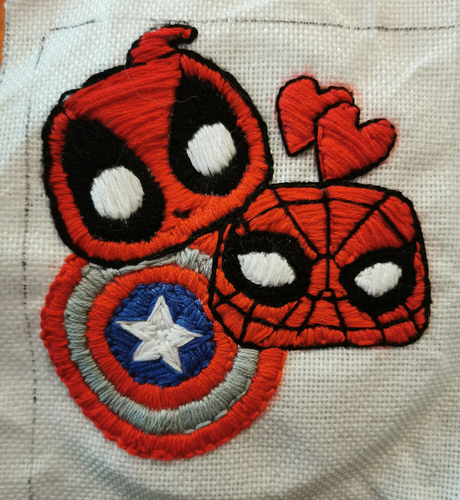 Embroidery. Two Funk-Pop heads. One being Deadpool and one being Spiderman. On obe side of tgem additional two littkw hearts and bebwatg them the blue, red, silver Captain America shield.