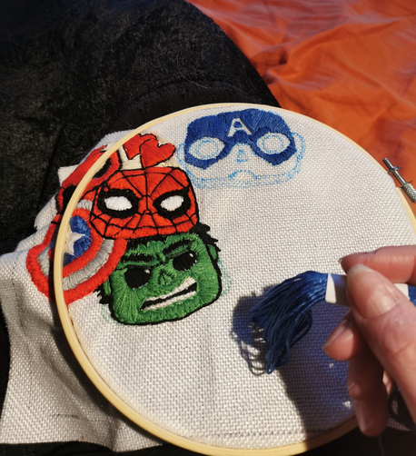 Foto of an embroidery prodject. Motiv: Marvel Characters in FunkoPop optic. In the making: the blue of the helmet of Captain America. Already finished: Hulk, Deadpool, Spiderman, Shield of Captain America