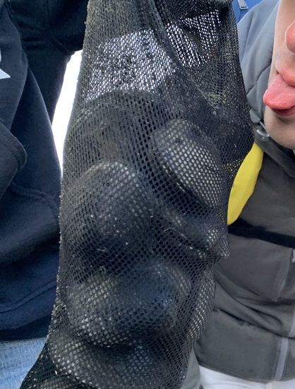 My brother sticking his tongue out precariously close to a clam bag full of butter clams.