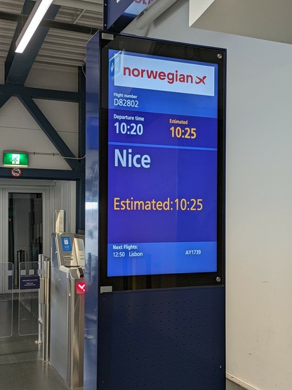 Screen at boarding gate showing Norwegian airlines flight D82802 heading to Nice, scheduled departure time 10:20, estimated departure time 10:25.
