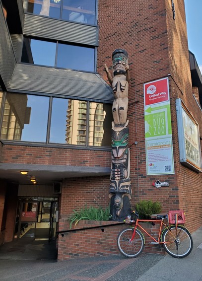 Entrance to Vic Theatre. Totem pole on the right. A red bicycle with red milk crate & rainbow straps is leaning on handrails at top of entrance walkway.