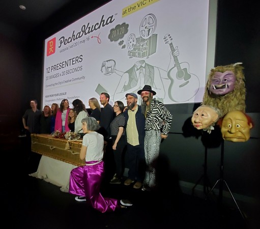Pechakucha presenters & emcee after event wrapped. 3 large full head masks are on far right.