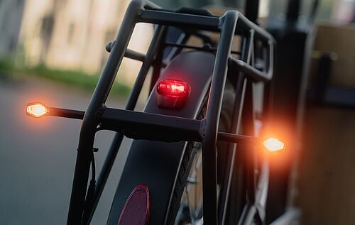 Zu sehen ist ein Fahrradpackträger mit seitlich angebrachten Blinkleuchten.