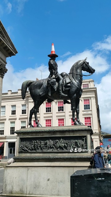 A right hand side profile of the Wellington on his horse Copenhagen statue in central Glasgow. The statue wears an orange traffic cone on his head at a rakish angle, it's apparently a Glaswegian thing...