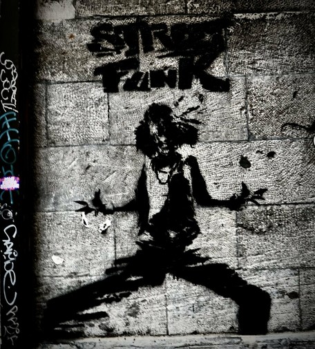 Graffiti art on a stone wall in a side street of Old Montreal. The artwork depicts a figure in a dynamic pose with the words "Street Punk" stenciled above.