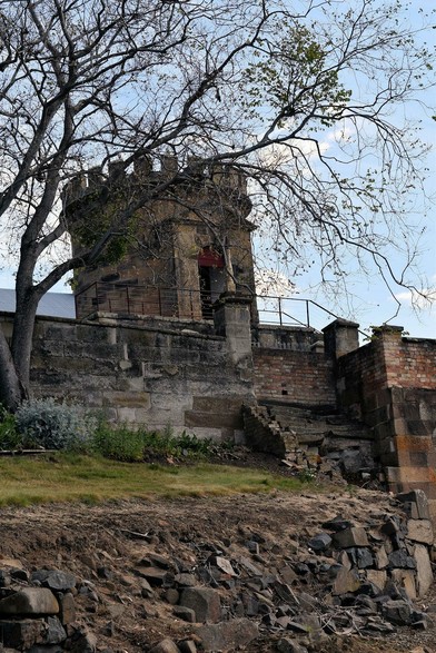 A short crenalated tower behind a stone wall. (It's actually a two-storey tower but the lower level is behind the wall). The front of the tower has a doorway with a pediment.
There are stairs leading up and behind the stone wall, but they're shattered and not usable.
In front of the wall is a grass bank with a small tree, with lots of branches, which are partly obscuring the tower.