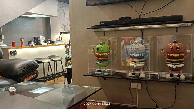 Photo of the interior of a bike shop. There are 3 hamburger characters on display, with faces on there to bun and hands holding utensils