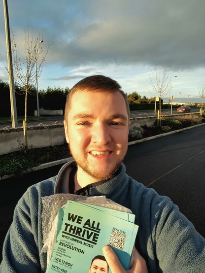 A selfie of Killian in the sunset light holding his fundraiser event flyers while out canvassing.