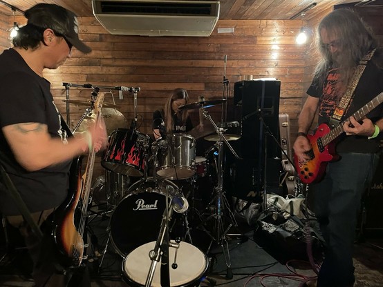 Blasting Rod: Avant Garde, Psychedelic, Hard Rock Jam Band. Photographed on stage, live at Koiwa Bush Bash, Tokyo, Japan. Cabin walls. Wood. Lumber. Pearl Drums. Yamaha Drums. Schecter Bass. Epiphone Les Paul Studio electric guitar. Joshua Tree patch. Tattoo. Trucker cap. Long hair. KMT Gong. ブラスティング・ロッド：アバンギャルド・サイケデリック・ハードロック、ジャム・バンド。東京都江戸川区小岩、ブッシュバッシュ。キャビン風。木材ライブハウス。コンサート写真。生演奏。パール・ドラム。ヤマハ・ドラム。シェクター・ベース。エピフォン・レスポール・エレキギター。タトゥー。トラッカー帽。長髪。ロンゲ。ロン毛。ジョシュアツリー・ワッペン。パッチ。ドラ。ロックＴ。ロックＴシャツ。バンドＴ。