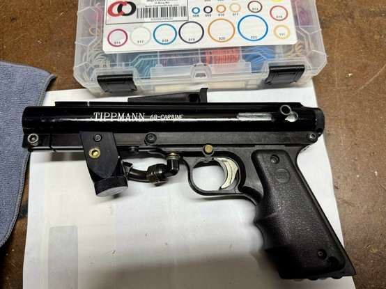 A black Tippmann 68 Carbine paintball gun, assembled on a workbench.