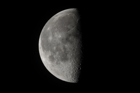 Der abnehmende Mond kurz vor Halbmond fast formatfüllend am dunkeln Nachthimmel