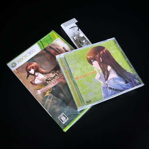 Zawartość opakowania z grą Steins;Gate: My Darling's Embrace na konsolę Xbox 360, wydanie japońskie – opakowanie z grą, brelok i ścieżką dźwiękowa na płycie CD.