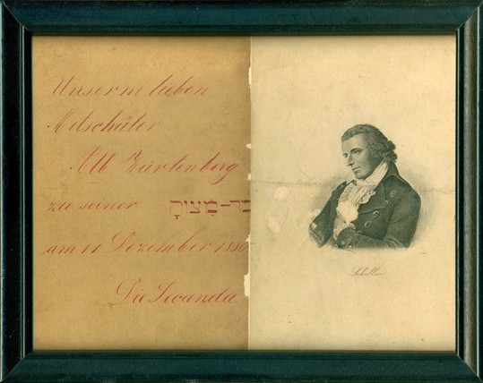 framed improvised greeting:

at right, a steel engraving of the poet Friedrich Schiller, after the portrait by Ludovike Simanowitz, perhaps/presumably taken from an edition of his complete or selected works

at left, on ordinary, more yellowed paper: inscription in red ink, German, in which pupils congratulate their dear friend in the occasion of his Bar Mitzvah (this term in Hebrew)