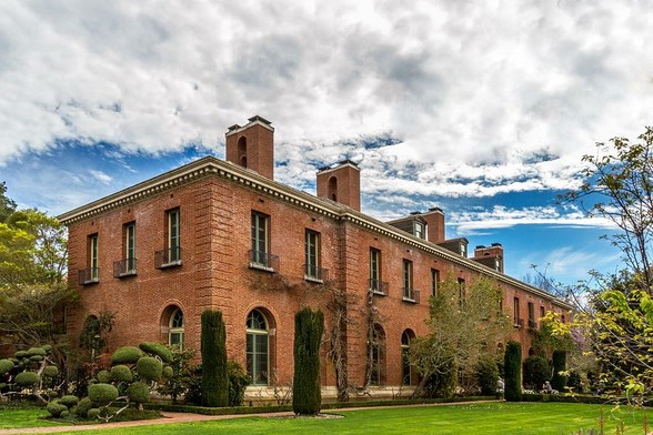 Filoli

This is an image of the Filoli Mansion located in Woodside, California.
This mansion is a two story brick building with 56 rooms and 54,256 square feet.
In this image you can see the backside of the building and some of the surrounding gardens.
The grounds of the mansion are completely manicured. The grass is closely cut and the bushes have all been sculpted.
The sky is mostly cloudy with a break a blue sky coming up over the building.