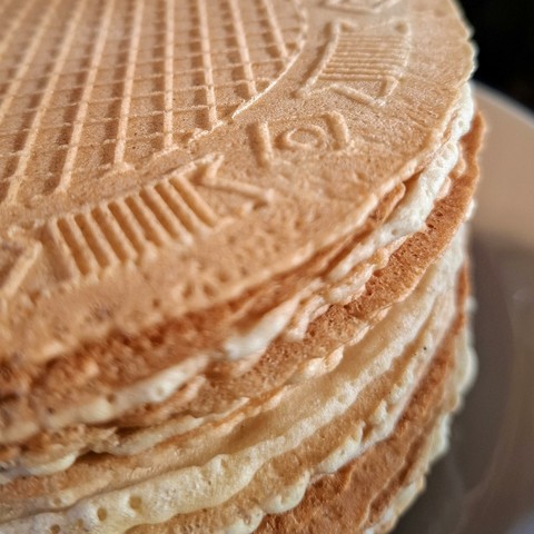 Close-up van een stapeltje goudgeel gebakken dunne wafels met een ruitjespatroon en decoratieve rand