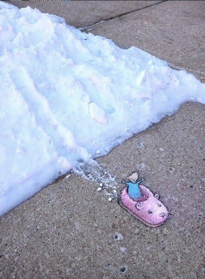 Streetart. A little mouse (named Nadine) has been drawn with chalk on a gray sidewalk with some snow on the edge. Nadine is standing in her long blue dress in a pink slipper next to the snow. Incidentally, the slipper has a cute animal face. There is a small trail of snow from the snow to the sidewalk because Nadine is using the slipper as a sledge. Beaming with joy and with her arms raised, she stands there and enjoys the slippery winter fun.
