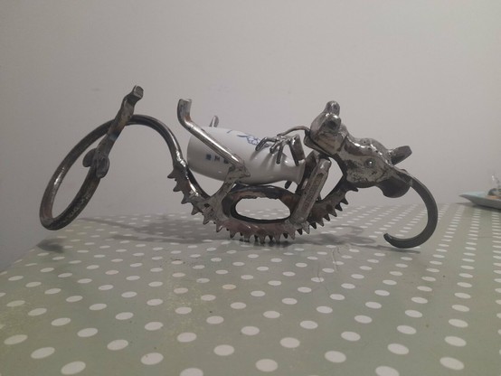 Dragon-like metal creature lying on its back cradling a ceramic, white sake bottle