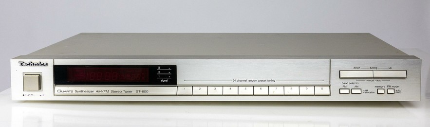 Frontansicht des Radioempfängers als Teil eines Hifi-Anlage. Links der Ein-/Ausschalter, daneben des Display, darunter die Steuerungstasten
