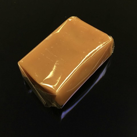 A minimalist, color photo of a piece of salted caramel wrapped in cellophane and resting on the screen of an iPad.