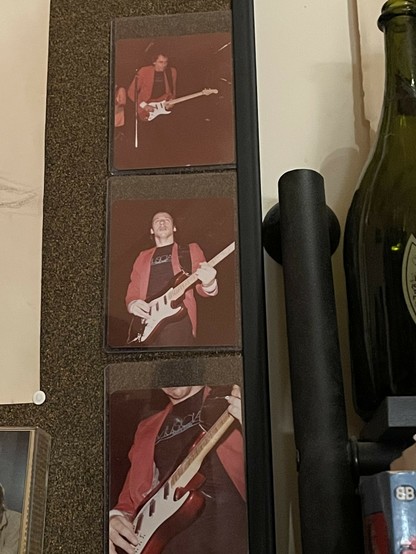 3 photos of my own on my bulletin board of Mark Knopfler on stage in progressively closer views playing his guitar.