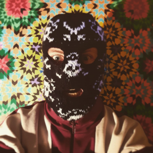 Ski-mask wearing man. Self-portrait. Islamic patterns in the background.