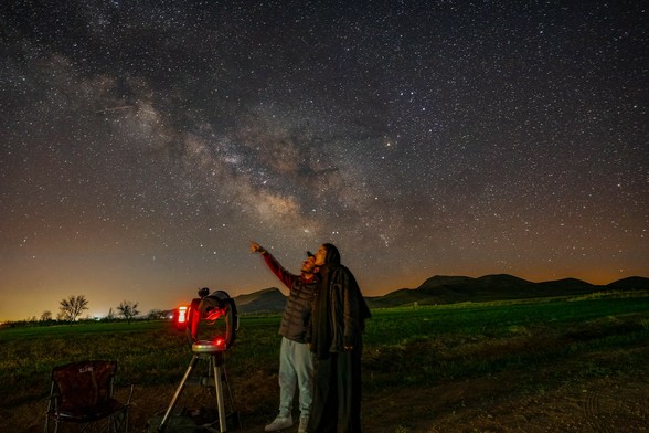 #Unsplash photo of two figures in the night. Both are looking in the same direction to the upper right where one is pointing up into the night sky. They have a telescope on a portable rig. There are low mountains in the distance, all with brilliant stars overhead with no clouds. 

Dated 2022 Jun 05, by Akbar Nemati. 
www.Unsplash.com/photos/a-man-standing-next-to-a-telescope-looking-at-the-stars-C74Egy7es14 

www.KronoMoon.org 🏳️‍🌈 ☮️
#KronoWatch