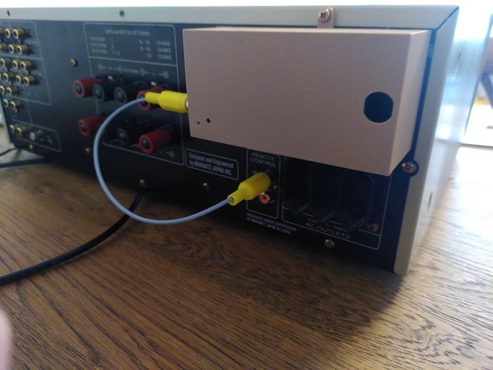 The back of a Marantz PM7200 amplifier with a 3D printed box attached to it, along with a RCA-RCA cable from the box to the amplifier.
