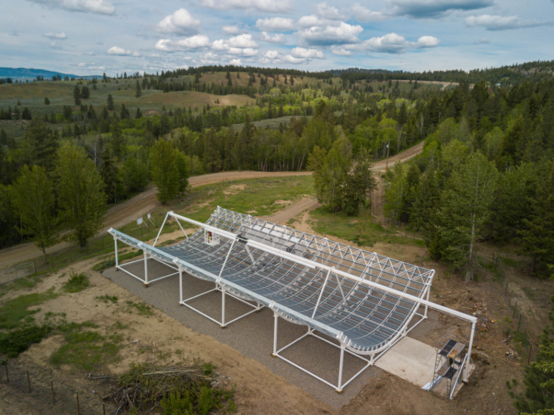 A radio telescope set amidst a land of hills and trees.