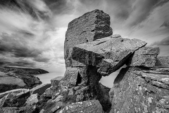 Stone formation on the steep coast. A stone slab lies across two rocks and offers another view of the sea.
