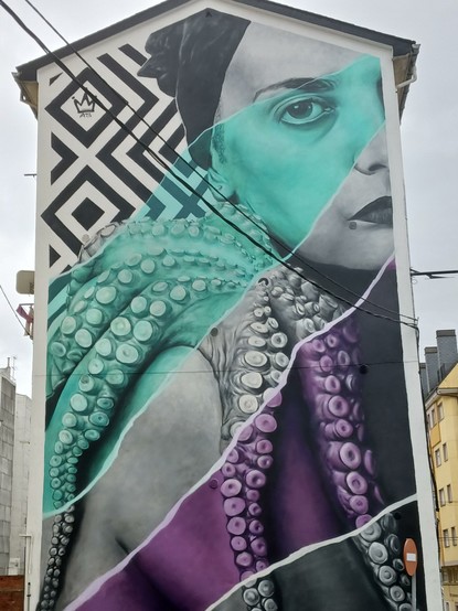 Mural/Grafitti cubriendo fachada del lateral de un edificio. Muestra a una mujer en ByN con un pulpo posado sobre su hombro.