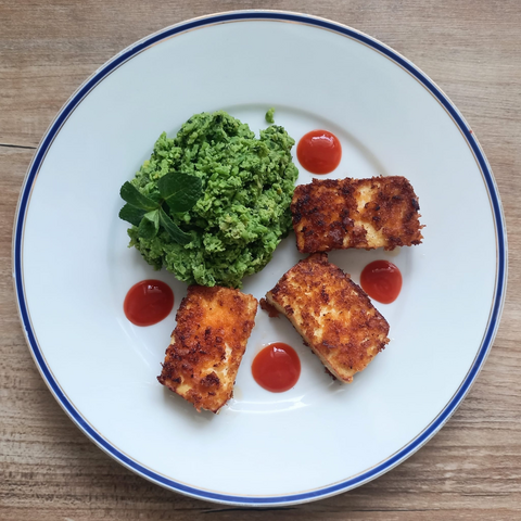 Das fertige Gericht auf dem Teller, dekoriert mit Tupfen von scharfer Sauce und einem Zweig Pfefferminze