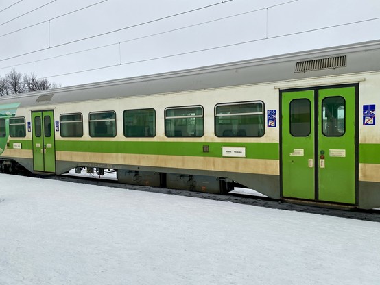 Yksikerroksinen lähiliikennevaunu lumisen asemalaiturin ääressä.