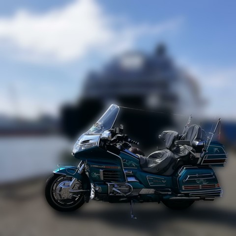 Motorrad Honda Goldwing, dahinter verschwommen ein Schiff auf der Mosel.