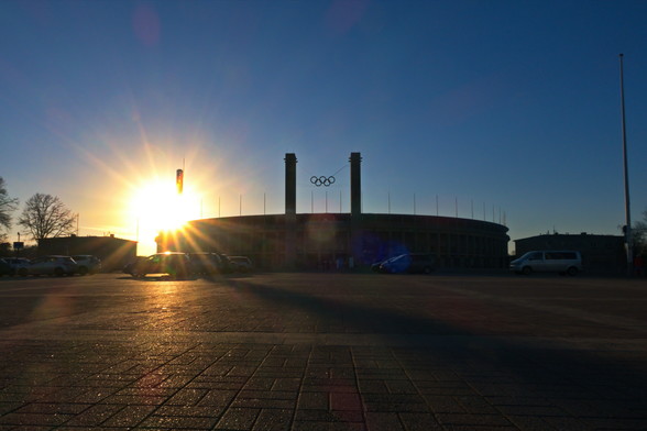 Das Berliner Olympiastadion vom Olympischen Platz aus gesehen.
An der rechten Ecke, am Glockenturm, geht die Sonne hinter dem Stadion unter.