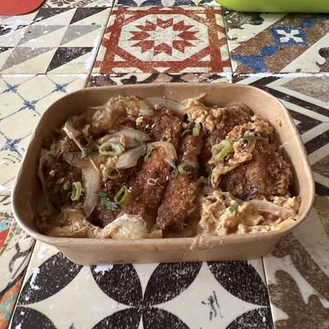Take Away box with katsudon inside, a dish of rice scrambled eggs and breaded pork cutlet