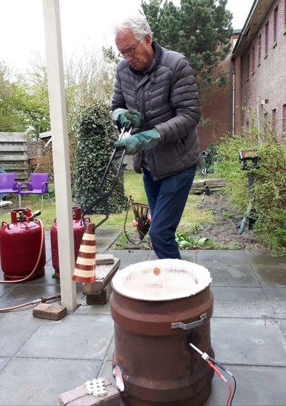 Man (Wybe Jansma) met grote rakutang waarin een roodgloeiend werk hangt dat net uit de raku-oven komt.