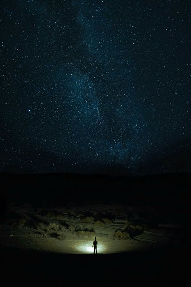 Unsplash image on a dark night shows a small, lone silhouetted figure standing at bottom center, facing away from us. They look toward a lighted area on the ground, possibly by pointing a flashlight. Beyond in the distance are black hills in shadow, but most of the picture is overwhelmed by a vast deep dark blue night sky above with millions of stars and galaxies. Mood is one of cosmic wonder. 
Captioned, "snow covered field under starry night / Download this free HD photo of iran, black, human, and person in Iran".

Iran 
Dated 2021 Aug 13, by 
Kiarash Mansouri.
www.Unsplash.com/photos/snow-covered-field-under-starry-night-7yIWldVlGks 

www.KronoMoon.org 🏳️‍🌈 ☮️ 
#KronoWatch